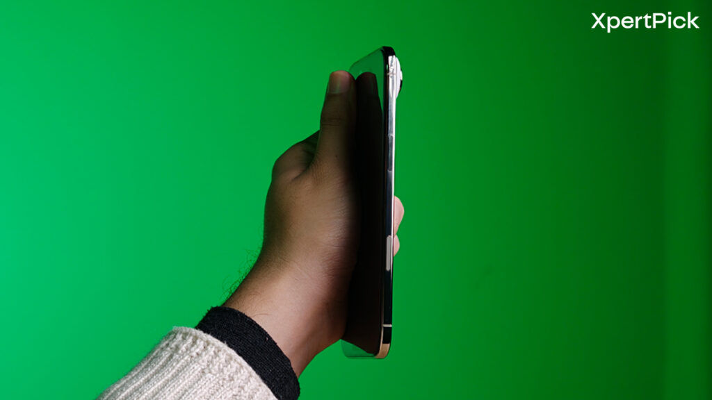 Side profile of the Apple iPhone Air held in hand, highlighting its slim chassis, power button, action button and flat metal frame against a green background (Source: Yetnesh Dubey / XpertPick)